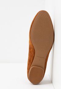 Vue de dessous d'une chaussure femme en daim marron montrant la semelle et le talon texturés avec le logo "Vagabond Shoemakers" et la taille 37.
