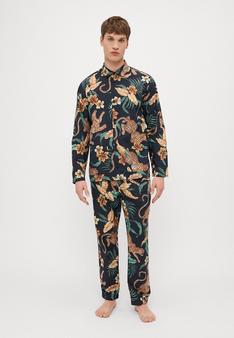 Garie uz long-sleeve pidžamu komplekts ar melnu fonu, uz kura ir ziedu un leopardu raksts zeltaina, zaļa un brūna toņos. Gluda auduma tekstūra.
