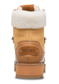 Tan suède enkellaars met een witte faux-fur kraag, leren hielpatch met "ROXY" logo en een bruine rubberen zool. Voorzien van gestikte accenten.