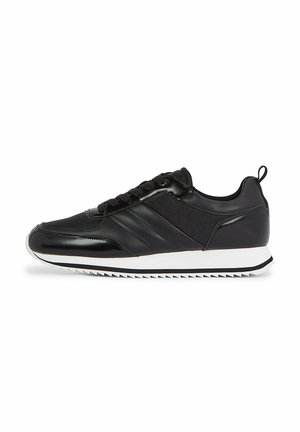 Zapatillas deportivas negras con una parte superior de cuero suave, paneles laterales de tejido texturizado, suela de goma blanca y cordones negros. Presenta una pestaña de sujeción en la parte trasera.