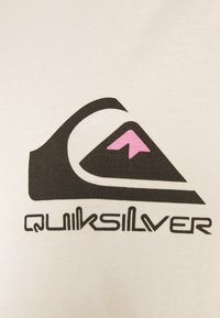 T-shirt bianca con logo Quiksilver nero e rosa, con un design stilizzato di montagna e onda. La texture appare liscia.