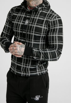Black and white plaid hoodie with a drawstring, featuring a logo in the center and ribbed cuffs. Paired with black pants displaying a logo.