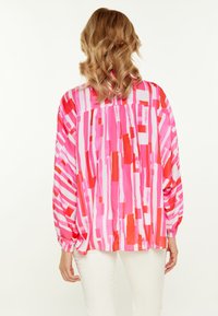 Langärmlige Bluse in leuchtendem Pink, Rot und weißen abstrakten Mustern. Mit plissiertem Rücken und luftigen Ärmeln. Leichter Stoff.