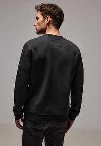 Sort crewneck sweatshirt i bl�ødt stof, med et rektangulært patch på den øverste del af ryggen, lange ærmer og ribbede manchetter og kant.