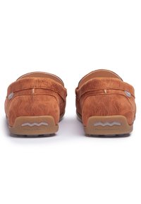 Brązowe zamszowe loafersy o teksturowanej powierzchni, z detalami przeszycia i gumowymi podeszwami. Podkreślone subtelnym logo na pięcie.