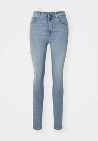 Pantalones ajustados de mezclilla en un tono azul claro. Presentan una cintura alta, cinco bolsillos y un cierre de cremallera con botón. Textura suave.