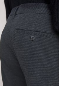 Dunkelgraue gestreifte Hose mit einem knöpfbaren Gesäßtasche und tailored Fit, die den fein strukturierten Stoff und das dezente Streifenmuster betont.
