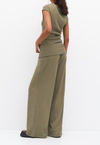 Ensemble composé d'un haut côtelé vert olive et d'un pantalon large. Le haut à manches courtes présente une coupe ajustée, tandis que le pantalon a une forme ample et fluide.