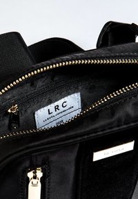 Interno di uno zaino in nylon nero con cerniere dorate, che presenta un'etichetta "LRC LA ROSA COPENHAGEN 2019" e una texture simile alla seta.