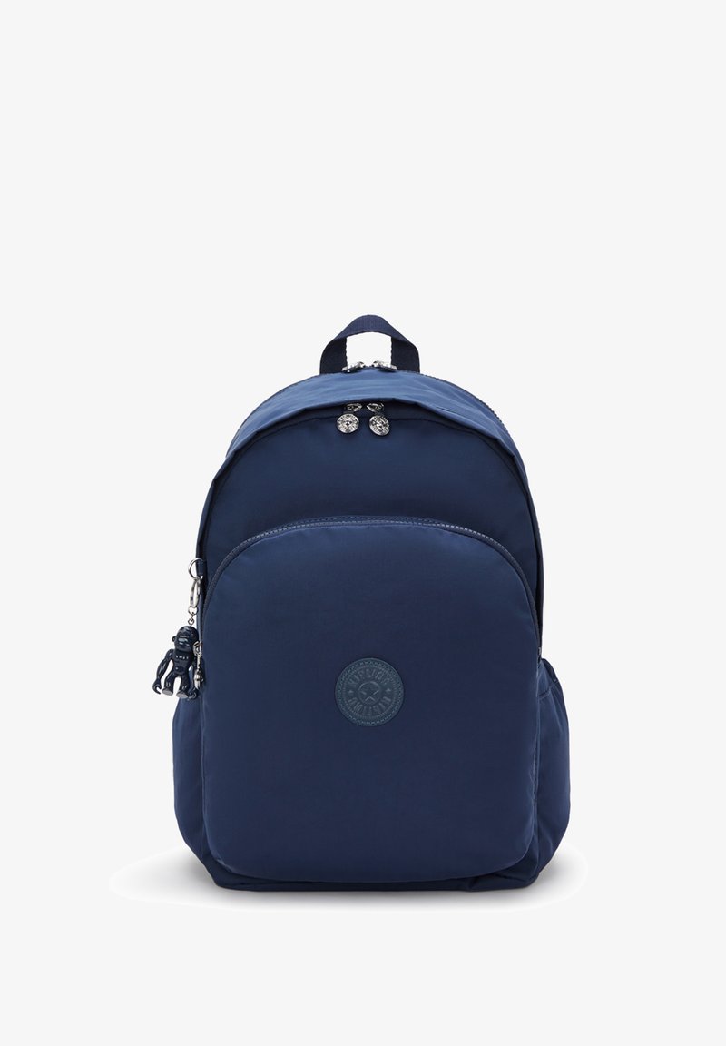 Navy blue nylonselkärepulla, jossa on pyöreä logo, vetoketjullinen etutasku, yläkahva ja koristeellinen avaimenperä. Sujuva pinta, pyöreä muoto.