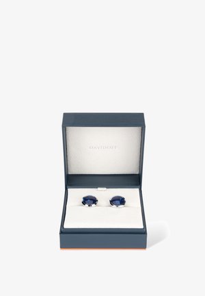 Silberfarbene Manschettenknöpfe mit tiefblauen Glassteinen, präsentiert in einer marineblauen Box, die mit weichem weißen Stoff ausgekleidet ist. Die Box verfügt über einen magnetischen Verschluss.