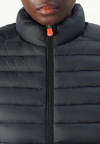 Black puffer jacket featuring a high collar, quilted design, front zipper with an orange pull tab, and smooth texture.