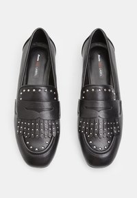 Musta nahkainen loaferit, joissa on niitatuilla yksityiskohdilla, kärjessä on frilla-design ja tasapohja. Silkkisen sileä pinta, ei näkyviä kiinnityksiä.