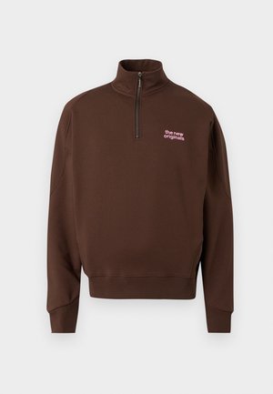 Rudas ilgomis rankovėmis puloveris su puse užtrauktuko priekyje, rožiniais užrašu „the new originals“ kairėje krūtinės pusėje, pasiūtais rankogaliais ir apačia.