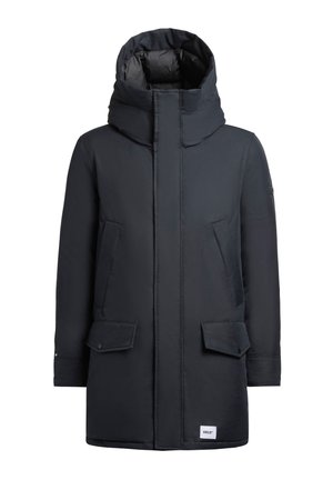 Cappotto lungo blu scuro con colletto alto, cuciture visibili, due tasche frontali e un logo sull'orlo inferiore. Tessuto dalla consistenza morbida.