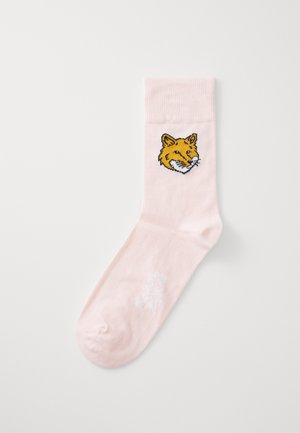 Meia de algodão rosa com uma cabeça de raposo amarela bordada no tornozelo. A meia possui uma textura suave e um comprimento padrão de cano.