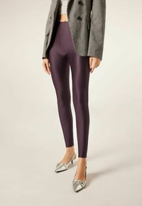Lilla højtaljede leggings i et skinnende, strækbart materiale, kombineret med en grå blazer og sølvfarvede stilethæle med spidse tæer og dekorative detaljer.
