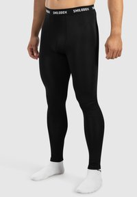 Mustat legginsit, jotka on valmistettu venyvästä kankaasta, jolla on sileä pinta. Varustettu mustalla vyötärönauhalla, jossa on valkoinen "SMILODOX" -brändäys.