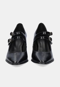 Zapatos de charol negro con punta afilada y dos correas ajustables con hebillas en el empeine. Textura suave y diseño minimalista.