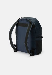 Marineblaues Rucksack mit einem weichen Stoffbezug, gepolsterten Schulterriemen, einer seitlichen Netz-Tasche und einer einfachen, abgerundeten Form. Minimalistisches Design.