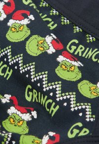 Granatowy materiał z wieloma twarzami Grincha w czapkach Mikołaja, zielonymi akcentami i wzorami w zygzaki. Napis "GRINCH" w jasnym zielonym kolorze.