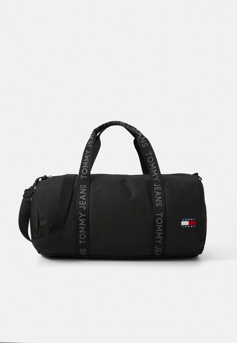 Μαύρη τσάντα duffel με λεία υφή, δύο κοντούς ιμάντες και αποσπώμενο ιμάντα ώμου. Διαθέτει ετικέτα με λογότυπο και λογότυπα στους ιμάντες.