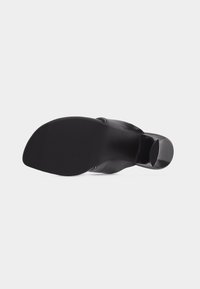 Μαύρο δερμάτινο μποτάκι αστραγάλου που φαίνεται από το πλάι της σόλας, με μυτερή μύτη και στιβαρό τακούνι τύπου block.