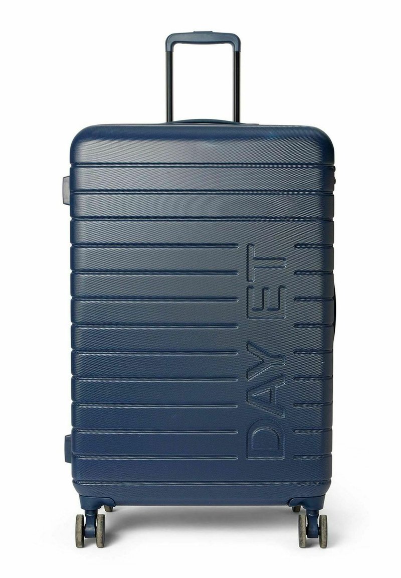 Valise rigide bleu marine avec une texture rainurée verticale, deux roues à roulement fluide, une poignée télescopique et une poignée latérale.