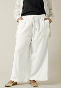 Witte wijde broek van zacht materiaal, met een elastische tailleband met verstelbare trekkoord en zijzakken.
