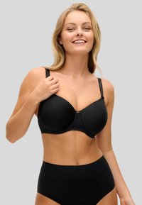 Musta rintaliivit, joissa on sileät, muotoillut kupit ja säädettävät olkaimet. Varustettu pitsireunuksella ja pienellä keskikohdan koristeellisella hakasella. Selkeä, minimalistinen muotoilu.