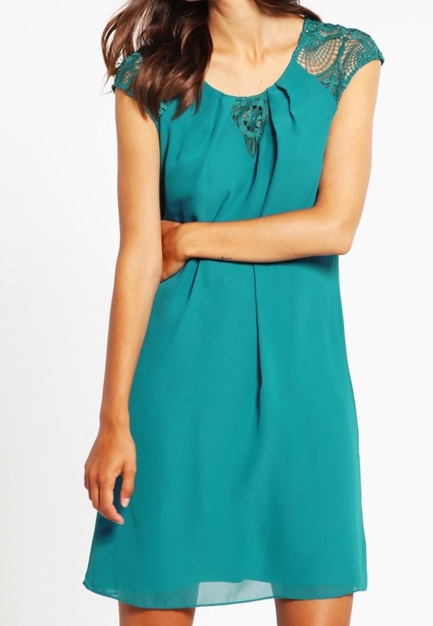 Turquoise jurk van lichtgewicht stof, met kanten accenten op de schouders en plooien aan de voorkant. Korte mouwen en een ontspannen pasvorm.