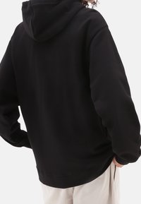 Sweat à capuche noir à coupe décontractée, avec des manches longues, une texture douce, et une poche kangourou à l'avant.