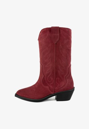 Red suede cowboy boot with pointed toe, black heel, and embossed swirl pattern. Features a pull tab at the top for easy wear.