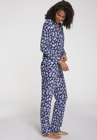 Pigiama blu composto da un set decorato con un design astratto di forme blu chiaro e bianche. Maniche lunghe e pantaloni con una vestibilità comoda.