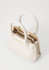 Beige lærveske med runde håndtak, gulllogo og glidelåser, strukturert form, med en innvendig organiser. Bredde: ca. 30 cm.