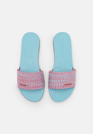 Sandales à glissière en caoutchouc bleu avec une sangle tissée rose et rouge, une semelle texturée pour une meilleure adhérence et une semelle extérieure noire.