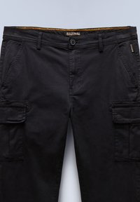 Black cargo pants made of cotton, featuring a flat front, multiple side pockets, and a textured waistband with a contrasting yellow stitch.