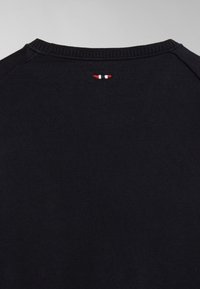 Camiseta de algodón negra con cuello redondo y un pequeño detalle bordado en rojo, blanco y azul en la parte posterior del cuello. Textura suave.