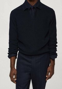 Maglione blu navy a maglia con scollo a V, maniche lunghe e design con colletto. La texture è a costine, abbinato a pantaloni scuri coordinati.