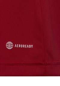 Maglietta sportiva rossa con logo AEROREADY in bianco. Il materiale ha una superficie liscia e strutturata, con un design aderente e senza pattern visibili.