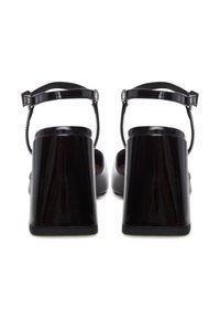 Sandali con tacco a blocco in pelle verniciata nera, con cinturini alla caviglia, caratterizzati da una finitura liscia e un design moderno.