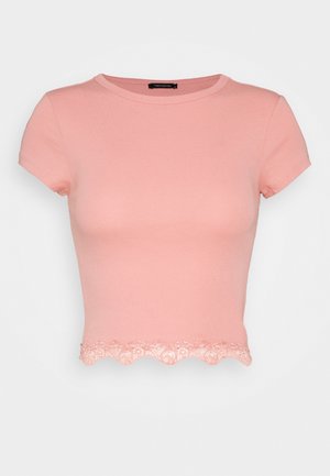 Pink short-sleeve t-shirt featuring a round neck and a scalloped lace hem detail at the bottom. Smooth fabric with subtle stretch.