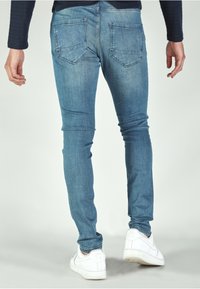 Skinny jeans in light blue denim, featuring a classic five-pocket design and subtle fading. Paired with white sneakers, the look is sleek.