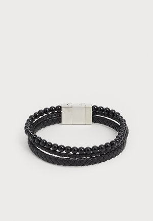 Black bracelet featuring woven leather and black beads, secured with a silver-tone clasp. Dual-strand design with textured and spherical elements.
