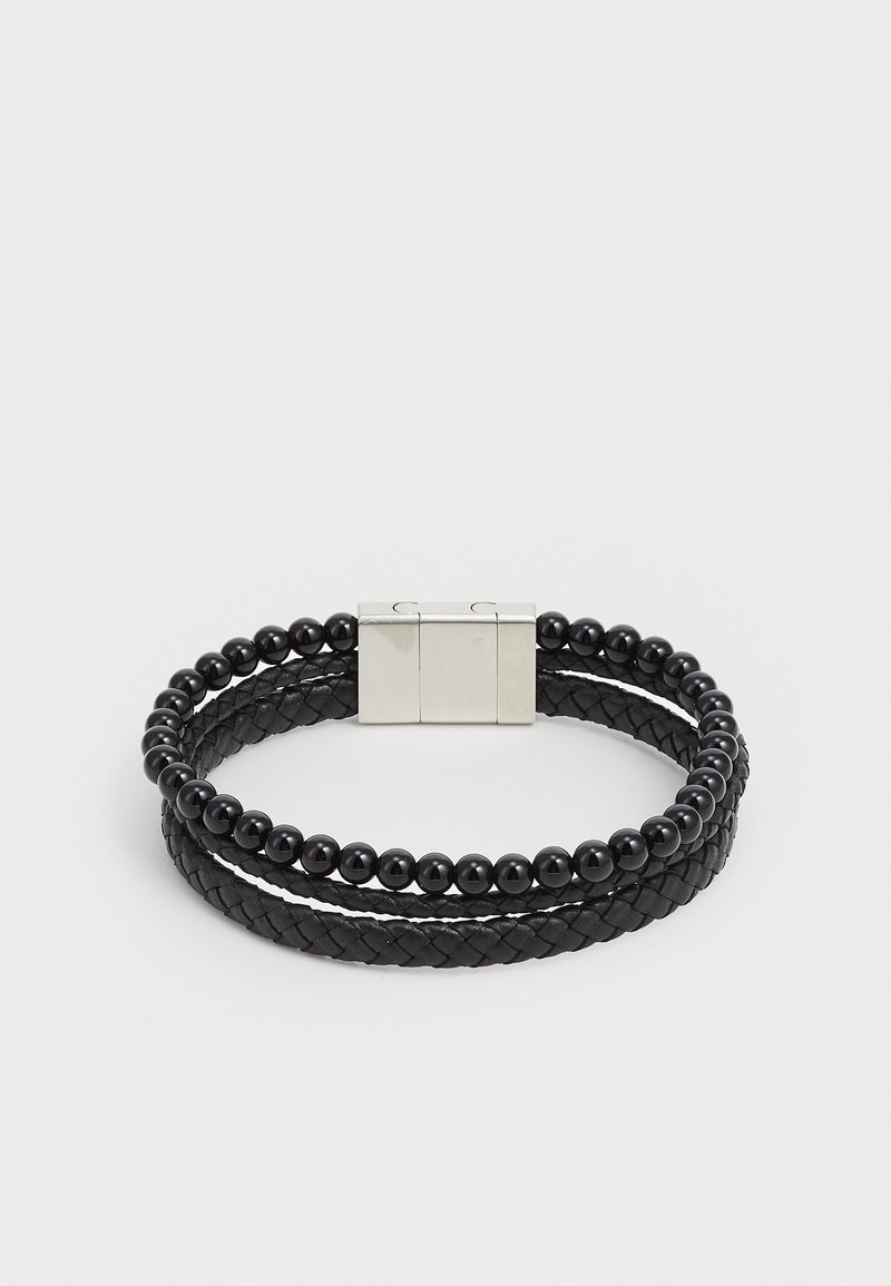 Brățară neagră cu piele împletită și cristale negre, asigurată cu un închizător din metal argintiu. Design cu două fire, cu elemente texturate și sferice.
