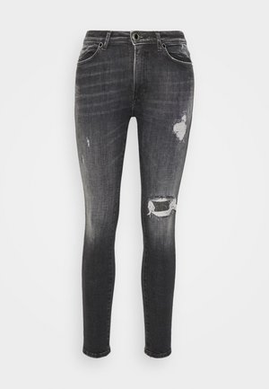 Mustat denimin kapeat farkut, joissa kulutuksen jälkiä, haalistunut viimeistely, repaleiset polvet ja perinteinen viiden taskun malli.