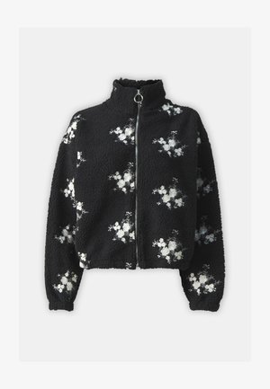 Black fleece jacket with high collar and front zipper, featuring white floral embroidery on the fabric. Soft texture, relaxed fit, long sleeves.
