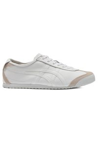 Baskets basses blanches avec des accents en daim beige sur les orteils et le talon, lacets blancs et semelle texturée, vues du côté extérieur.