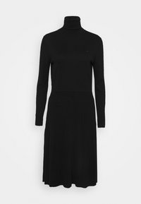 Robe noire en tricot avec un col roulé haut, des manches longues et une jupe plissée. Le tissu a une texture lisse et un minimum de détails.