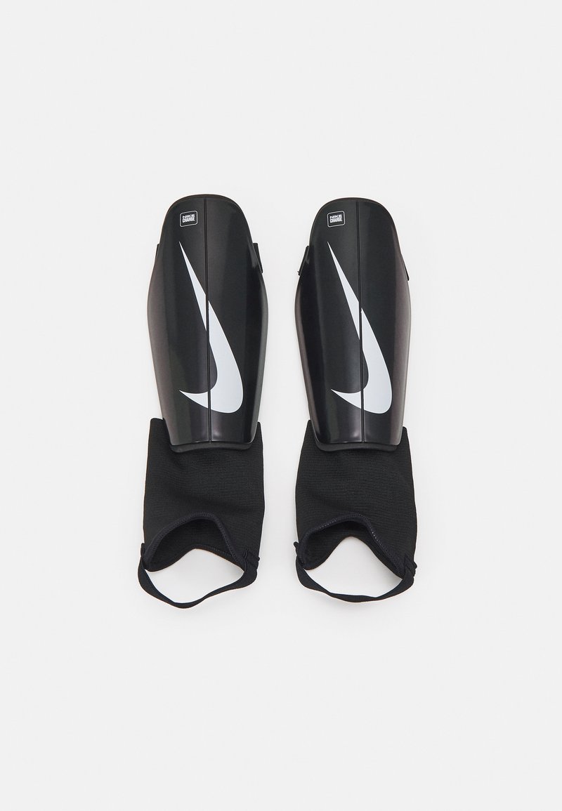 Espinilleras negras con un acabado brillante, que presentan un prominente logo blanco de Nike. Correas de tela negra suave para asegurar las espinilleras.